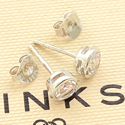 Sterling silver Links of London crystal stud earrings displayed on a yellow background with the brand's logo visible.