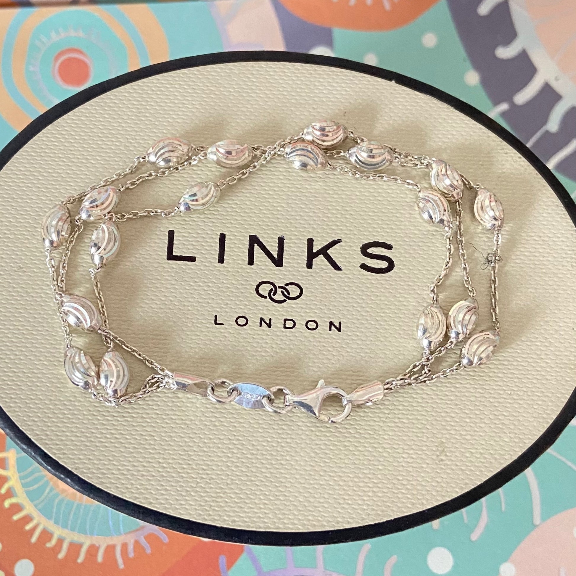 Silver bracelet on a 'Links of London' branded box with a colorful background