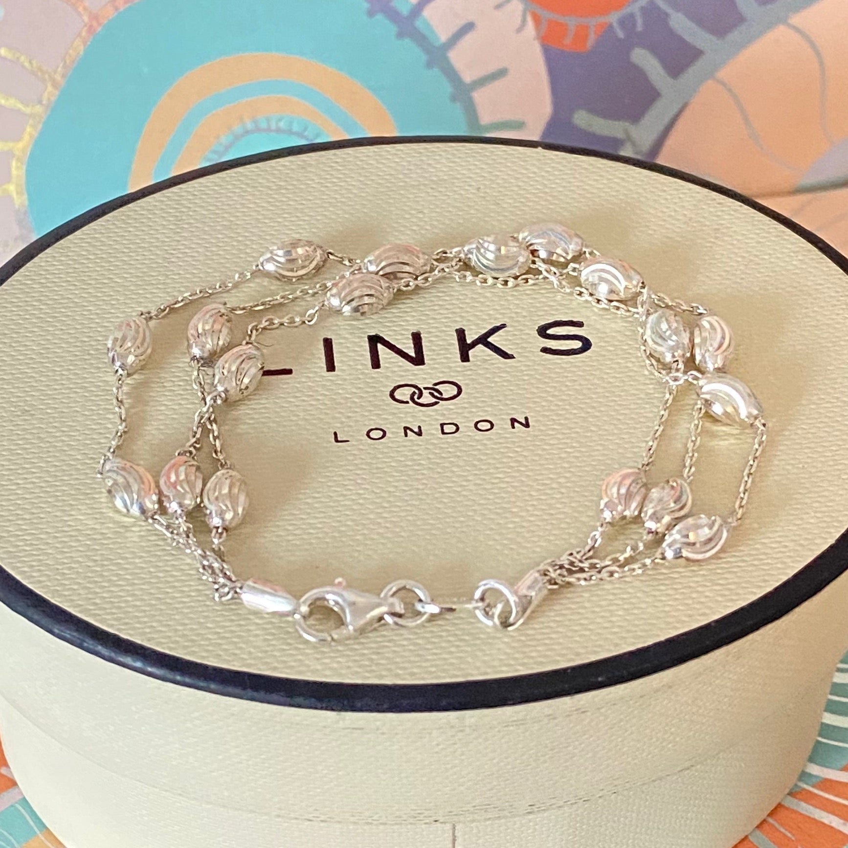 Silver bracelet on a 'Links of London' branded box with a colorful background