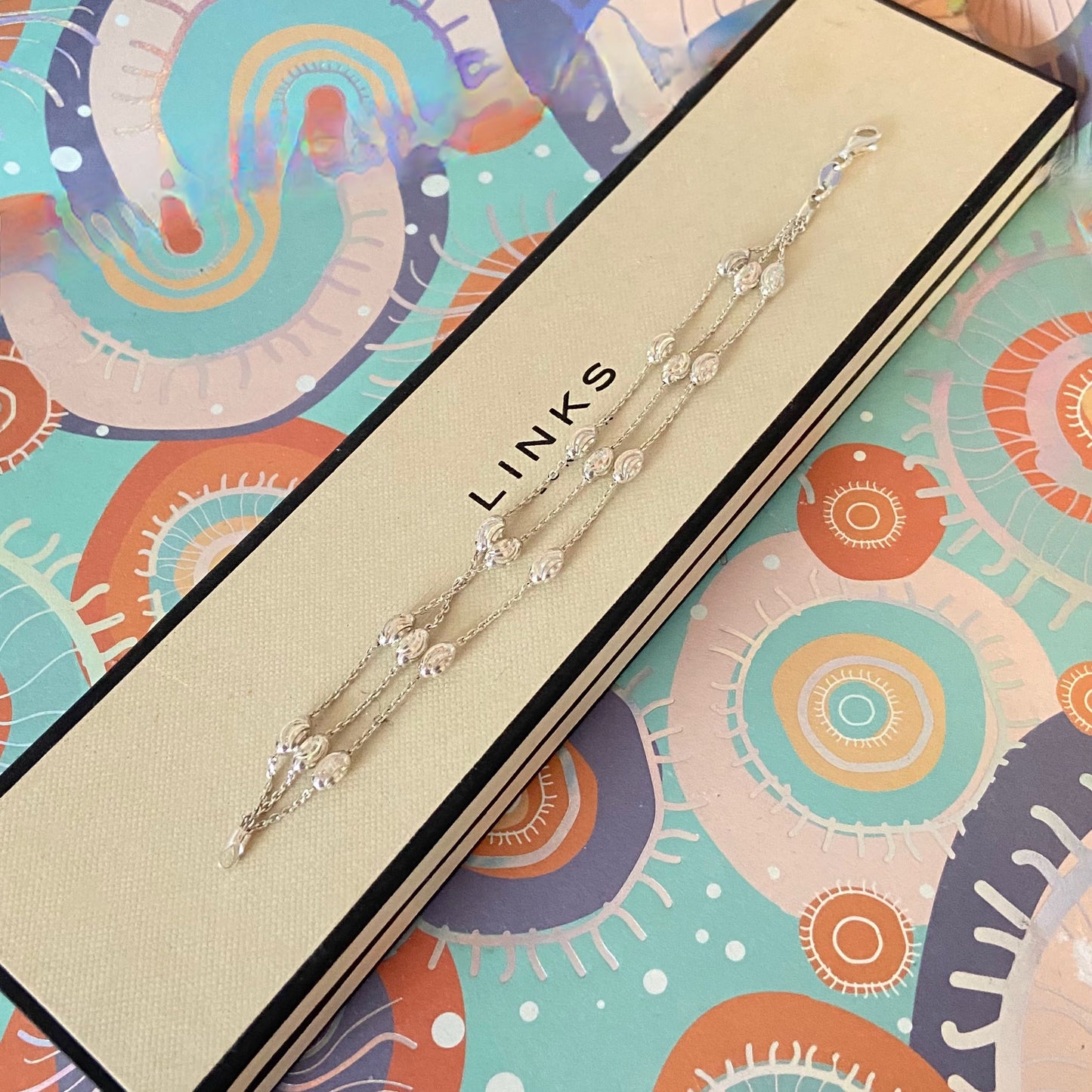 Jewelry box with a necklace labeled 'LINKS' on a colorful abstract patterned background