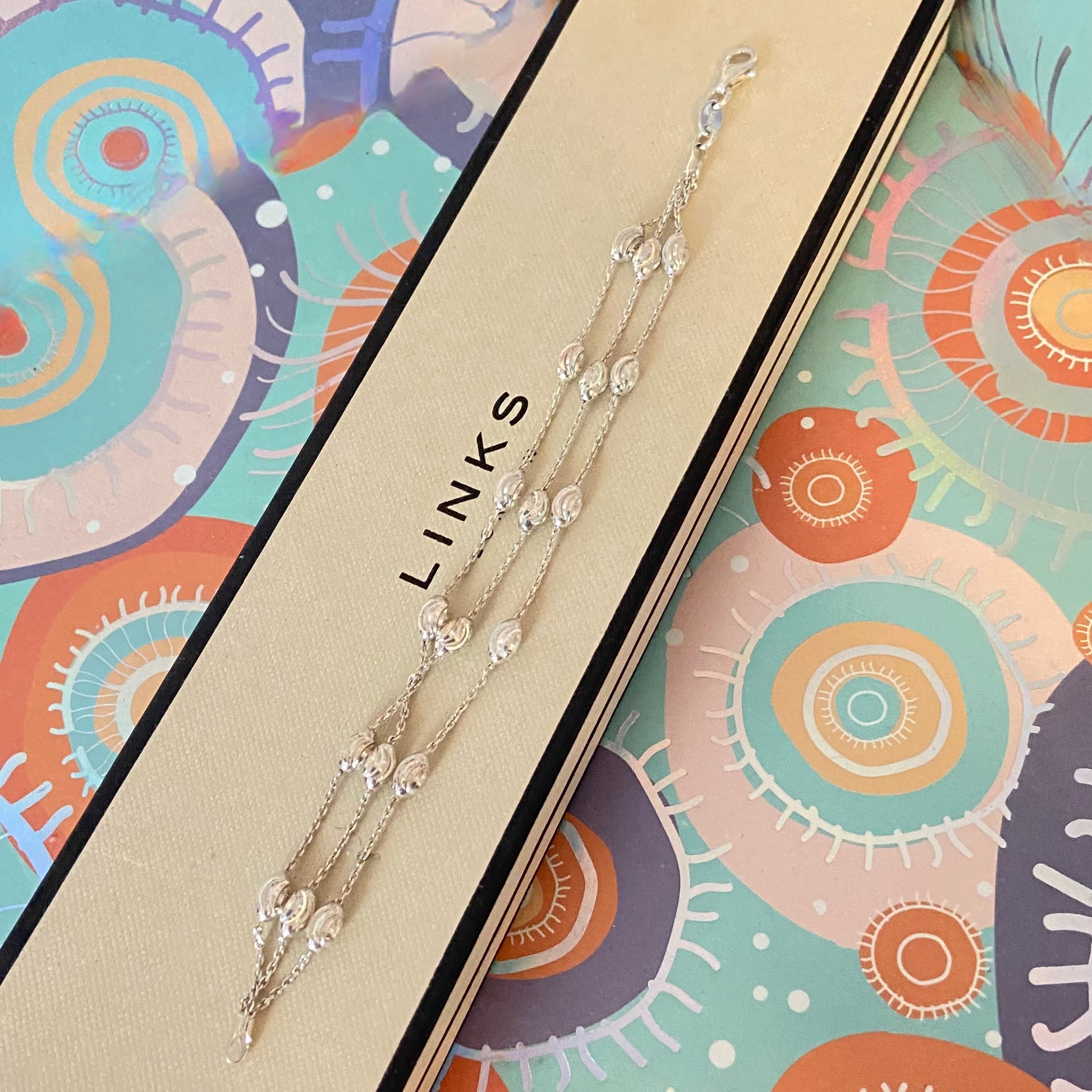 Silver necklace on a colorful box with 'LINKS' branding