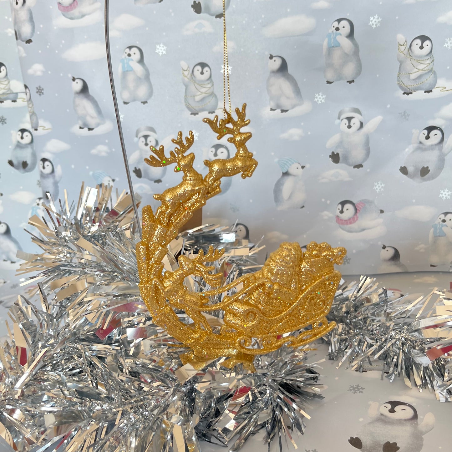 Sparkling, glitter-dusted gold reindeer and Santa sleigh hanging Christmas tree decoration.