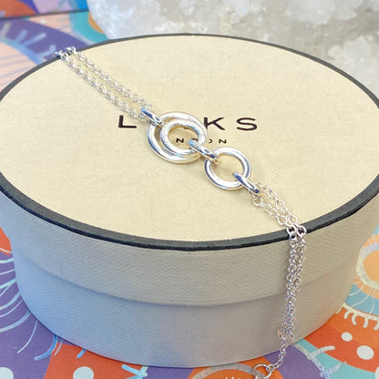 Links of London Sterling Silver interlocking rings resting on a double-strand chain bracelet