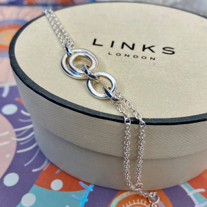 Links of London Sterling Silver interlocking rings resting on a double-strand chain bracelet