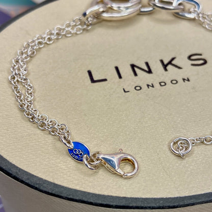 Links of London Sterling Silver interlocking rings resting on a double-strand chain bracelet