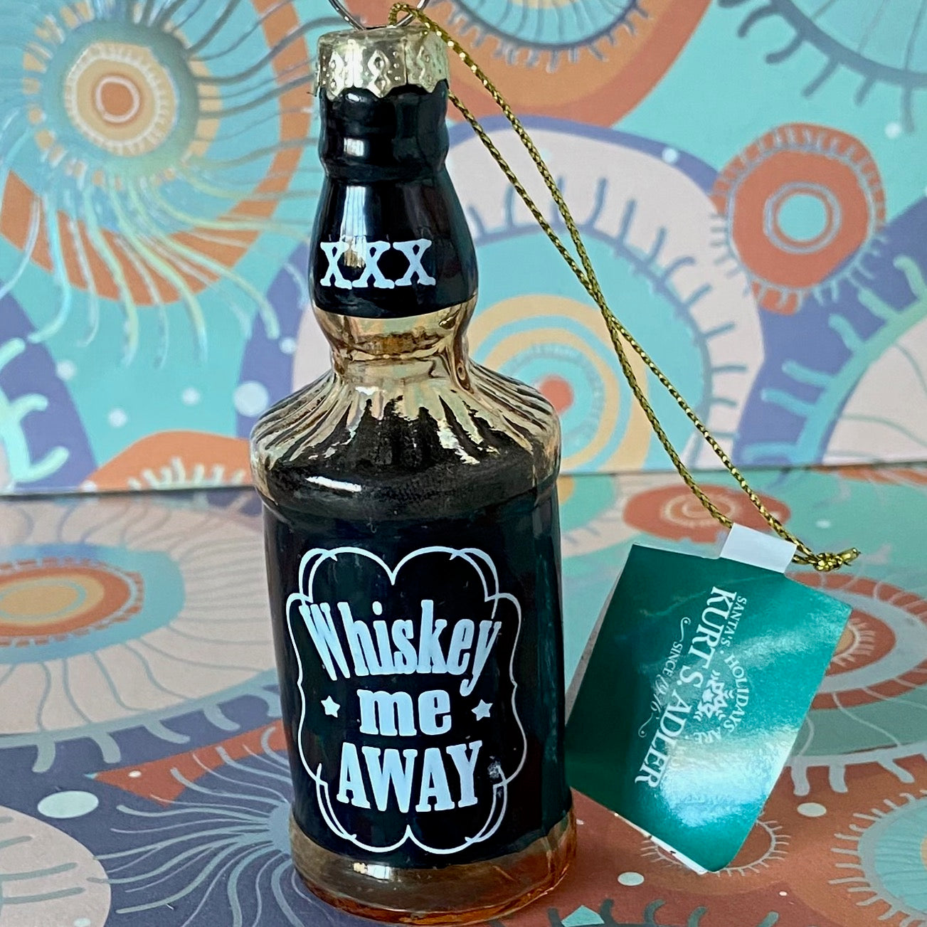 The item is a glass "Whiskey me AWAY" Christmas ornament, often manufactured by brands like Cody Foster & Co. or Kurt Adler.