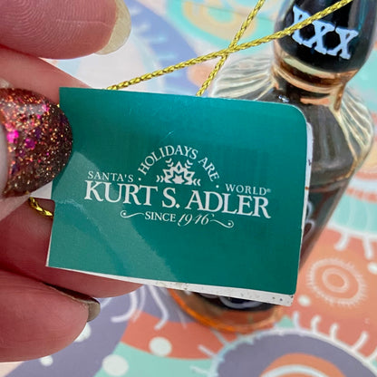 The item is a glass "Whiskey me AWAY" Christmas ornament, often manufactured by brands like Cody Foster & Co. or Kurt Adler.