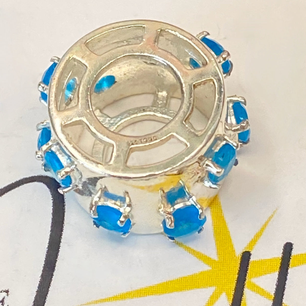 925 sterling silver charm with blue gemstones, featuring the hallmark maker's mark TGGC.